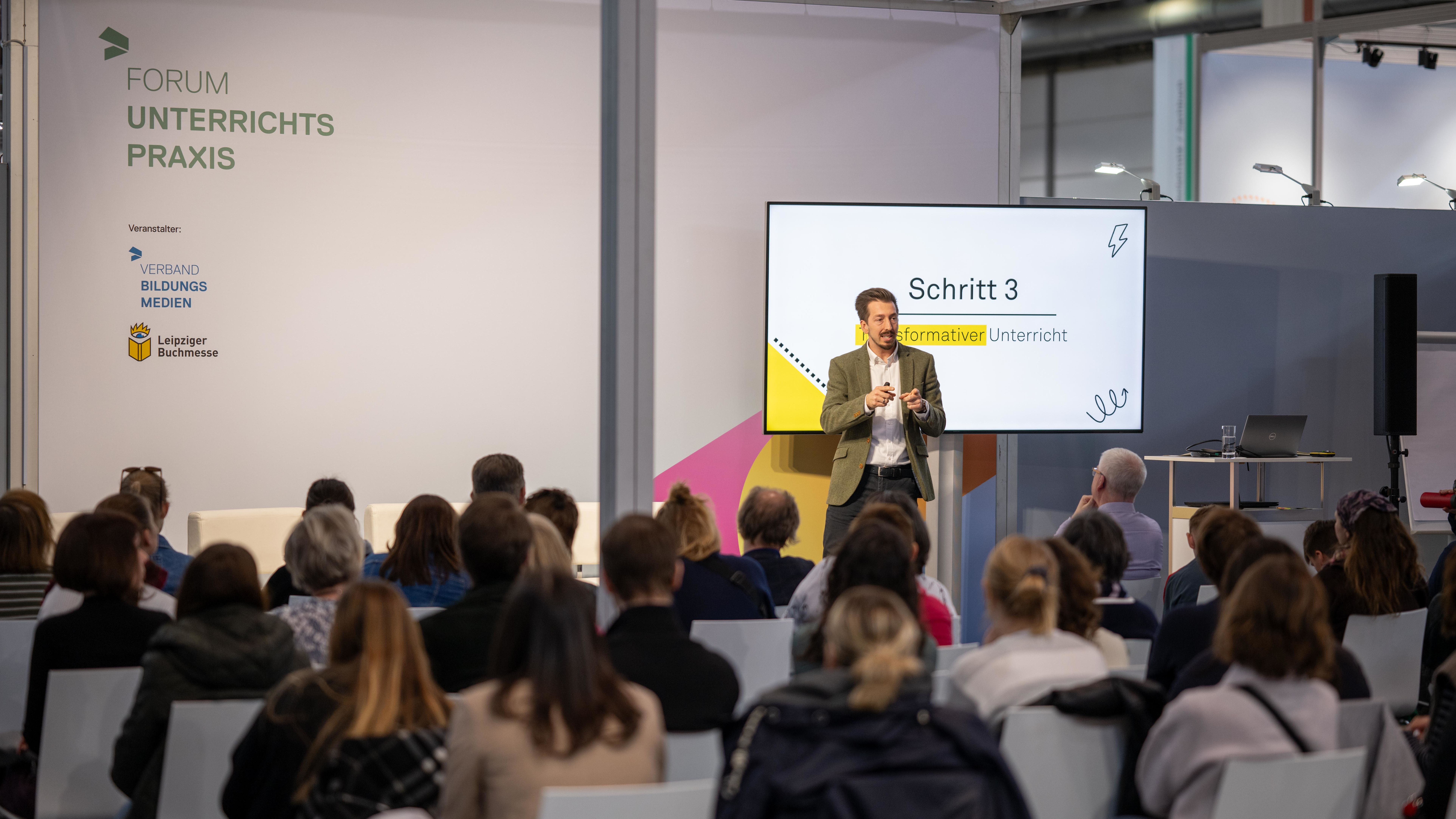 Ein Referent hält einen Vortrag in einem gefüllten Seminarraum