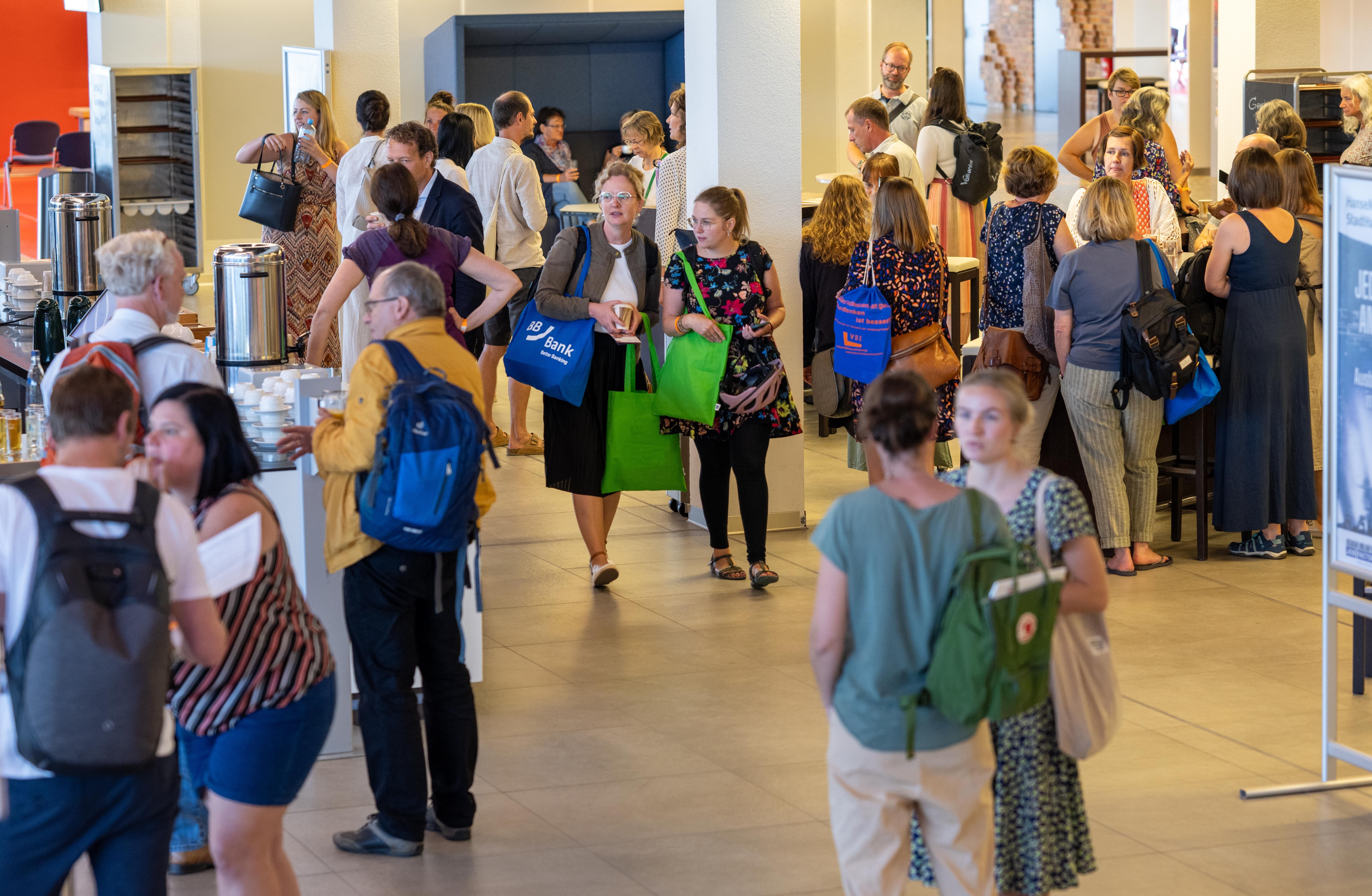Menschen stehen im Foyer und unterhalten sich miteinander.