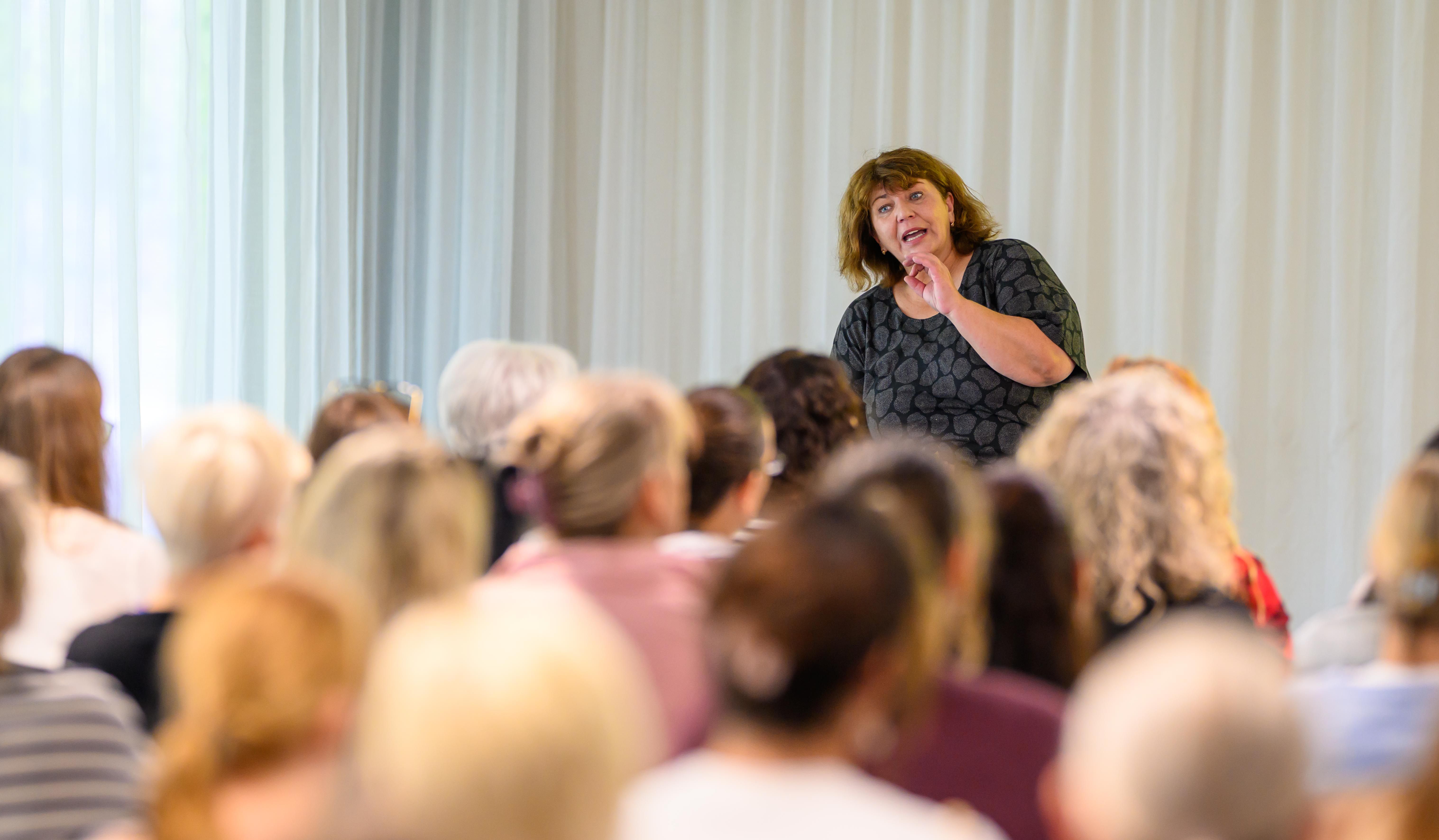 Eine Referentin in einem Workshop spricht zu ihren Teilnehmerinnen und Teilnehmern.